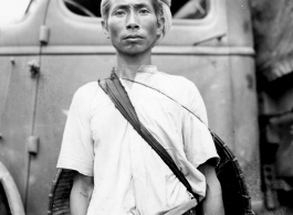 Local people in Burma near the 797th Engineer Forestry Company--A man poses in front of GI truck.  During WWII.