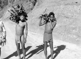 Men carry firewood on road in Burma.  Near the 797th Engineer Forestry Company.  During WWII.