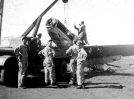 12th Air Service Group mechanics salvage a P-51 fighter in Guangxi, China, during WWII, cranking the aircraft up onto a flatbed truck.