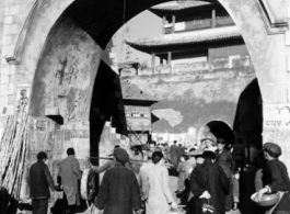 Civilians come and go at a gate in a city wall in China during WWII.