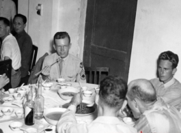 16th Combat Camera Unit members enjoy a banquet in China during WWII. Hal Geer holds up a jiaozi (饺子) in his chopsticks as he looks at the camera.