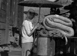 A Chinese refugee making shade from the hot sun between train cars. At the train station in Liuzhou during WWII, in the fall of 1944, as the Japanese advanced during the Ichigo campaign.