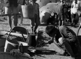 Chinese refuges tends a cooking fire to boil water next to the train tracks in Liuzhou during WWII, in the fall of 1944, as the Japanese advanced during the Ichigo campaign.