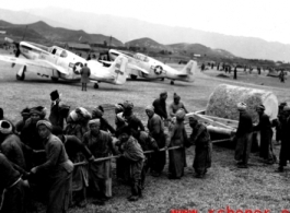 Laborers in China pull a concrete roller at an airbase, with parked P-51 fighters in the background. This was likely in SW China.  From the collection of Hal Geer.