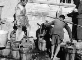 Town people in China get water in wooden buckets and shoulder poles during WWII.