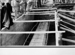 Pouring a concrete foundation as part of American air base construction in China during WWII.  Chinese laborers pouring concrete into forms.