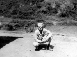 Douglas Runk squatting on road in SW China, during WWII.