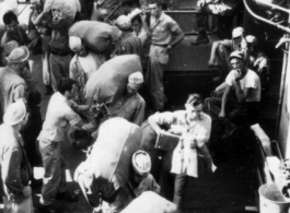 GIs board ship on the way back to the US after the war. The ship is probably the SS Marine Raven.