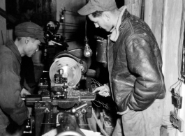 American and Chinese men work together at a lathe.  Image from U. S. Government official sources. 