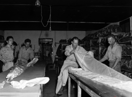 Packing and checking parachutes--a truly vital and exacting task. At an American base, China, during WWII.