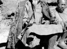 An elderly Chinese man at rest in the CBI, long pipe in hand.  From the collection of Wozniak, combat photographer for the 491st Bomb Squadron, in the CBI.