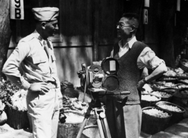 An American photographer (left) talks to a civilian, probably also a photographer (right), at a market in a village in Yunnan province.