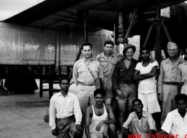 American and Indian service crew members pose for the camera in front of a B-24 up on jack and undergoing maintenance. 61st Air Service Group.