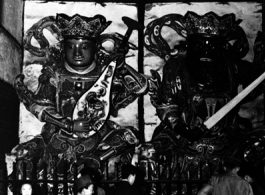 People look at the protective deities at the entrance to a Buddhist temple in China during WWII.