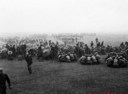 Chinese soldiers gathered in small groups to eat a meal in a pounding rain. During WWII.