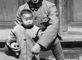 Local people in China during WWII: A Nationalist Chinese soldier holds a toddler during WWII.