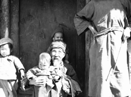 Local people in China: A poor elderly couple in a village watch over young children. During WWII.
