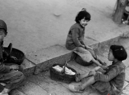 Local kids in China during WWII play on street curb.  From the collection of Eugene T. Wozniak.