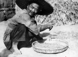 Local people in China: A farmer picks through grain to clean it.