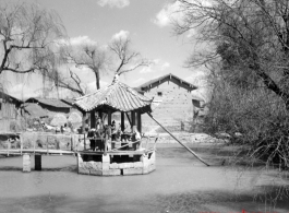 Local people and American visitor in a pavilion over a small pond near Yangkai,  Yunnan province, China. During WWII.