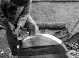 A craftsman repairing a wooden wheel in WWII China. 
