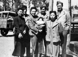 An elite Chinese woman holds a baby, and poses with American servicemen and local people in Yunnan province, China, during WWII.
