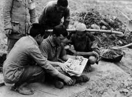 During a short rest period from the construction of an airfield (maybe at Chengdu), Chinese laborers look at "Life" magazine held by Lt. Otto of Troy, New York, in China during WWII.