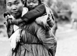 Refugee child being carried while fleeing around either Liuzhou or Guilin during the evacuation before the Japanese Ichigo advance in 1944, in Guangxi province.