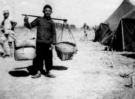 Scenes around Kunming city, Yunnan province, China, during WWII: Worker shoulders pole at GI tent camp.