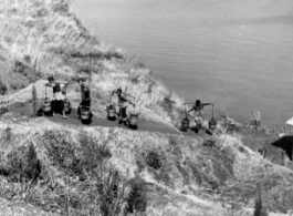 Chinese laborers extract water from the lake near Camp Schiel, Yunnan province, to use to build a road, work done by hand tools and hard labor. During WWII.