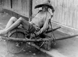 Farming in China: Farmer resting on wheelbarrow.