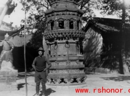 A westerner stands in front of a large incense burner in a temple in China during WWII.