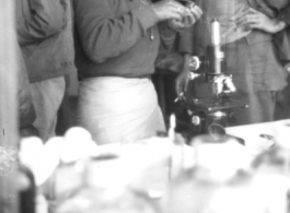 A chinese medical technician works while a cigarette smoking GI looks on.  Provided by Robert Babinec.  In the CBI during WWII.