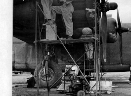 Near the new runway, Sgt. Neibuhr, Cpl. Carning, and Cpl. Zamoidu repair of a bullet hole in a B-24 in the CBI. Photo by Capt. Charles S. Welbourne. 1943.