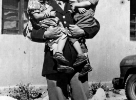 Chennault holds Tayng Wong and Toong Di, who had come with Col P. Y. Shu, interpreter, to present Chennault Christmas greetings written by grade school children. During WWII.