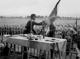 Chinese soldiers in ranks observe ceremonial hand off of banner or flag.