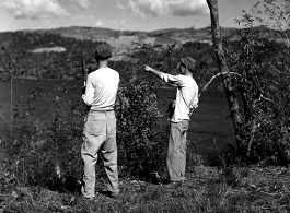 GIs stand carbine in hand looking over the lake.