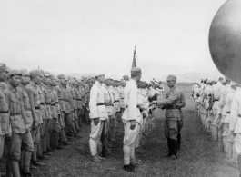 Chinese soldiers stand in ranks during exercises, being inspected by officers.