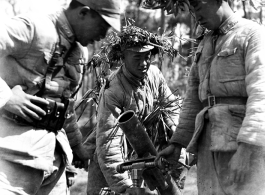 Chinese soldiers with mortar ready, and covered in camouflage during exercises in southern China, in Yunnan province.  Despite the appearance of being on their way to battle, these men are more likely in fact prepared for a demonstration or honor parade. 