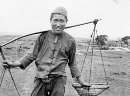 A farmer poses with a shoulder pole near an American air base in Yunnan, China, during WWII.