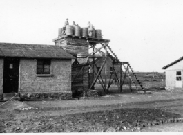 Workers fill water tank at an American base in Yunnan, China, during WWII.  GIs sitting on wooden platform.