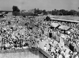 Expansive and busy market crowded with people.  Scenes in India witnessed by American GIs during WWII. For many Americans of that era, with their limited experience traveling, the everyday sights and sounds overseas were new, intriguing, and photo worthy.