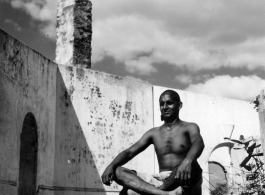 Man sitting cross-legged in India in 1943.  Scenes in India witnessed by American GIs during WWII. For many Americans of that era, with their limited experience traveling, the everyday sights and sounds overseas were new, intriguing, and photo worthy.