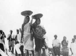 Women carry baskets of crushed stone on their heads.  Scenes in India witnessed by American GIs during WWII. For many Americans of that era, with their limited experience traveling, the everyday sights and sounds overseas were new, intriguing, and photo worthy.