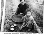 A Chinese woman and child start a fire next to a pipeline in which gasoline is flowing, 15 miles out of Kunming, next to the road to Chenggong (Chengkung). During WWII.