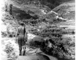 Cpl. Arthur Hedge, of 164th Signal Photographic Company, with carbine over shoulder, hikes trail towards Salween River campaign, 1944.