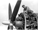 An American aircraft mechanic doing maintenance sits astride a large aircraft engine. In the CBI during WWII.