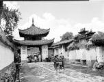 A whitewashed village street in Luliang, Yunnan, China, with a small gate tower towards the left, and ceremonial arch on the right. Local people in China.