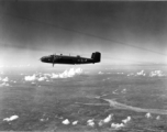 A B-25 Mitchell bomber in flight in the CBI, in the area of southern China, Indochina, or Burma, during WWII.