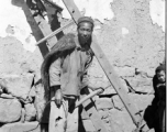 A farmer in a village near Yangkai shoulders a rake used to gather roots and stalks from ground that has been plowed. During WWII.